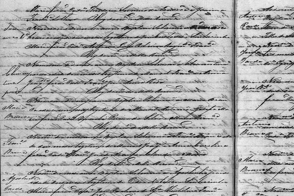 registro-paroquial-caligrafia-dificil-paleografia Página de livro de batismos antigo com caligrafia cursiva densa e difícil leitura, mostrando anotações marginais de nomes como Maria e Francisco.