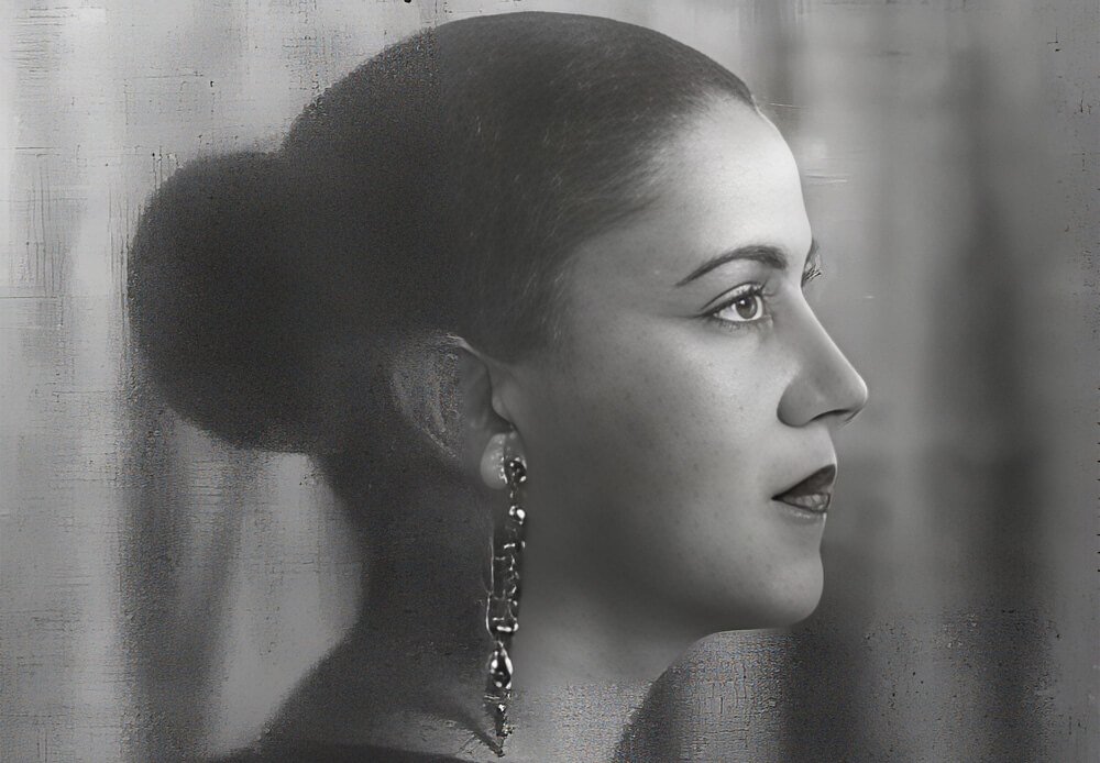  Retrato fotográfico em preto e branco de Tarsila do Amaral em perfil, com coque, brinco longo e expressão serena